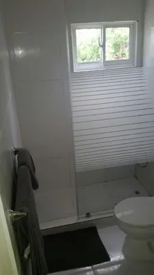 a white bathroom with a toilet and a window at Casa Vasquez in San Felipe de Puerto Plata