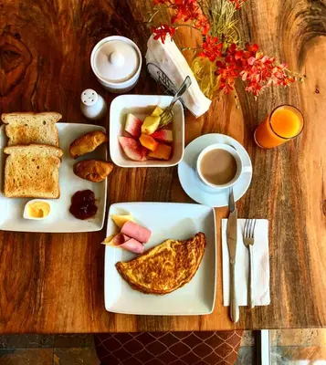 a table with two plates of food and a cup of coffee at Nilka Hotel Boutique in Santa Bárbara de Samaná