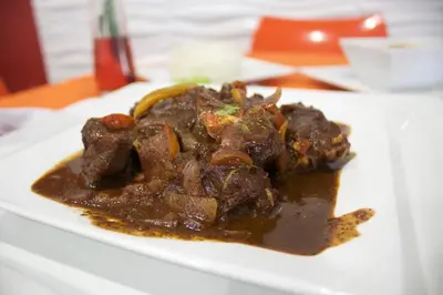 a plate of food with meat and sauce on a table at Gran Hotel Marien in Sabaneta