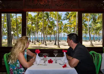 a man and woman sitting at a table with a view of the beach at Playabachata in San Felipe de Puerto Plata