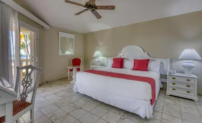 a bedroom with a large white bed with red pillows at Playabachata in San Felipe de Puerto Plata