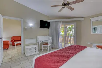 a bedroom with a bed and a desk and a ceiling fan at Playabachata in San Felipe de Puerto Plata