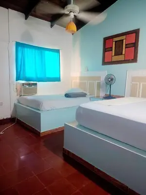 a bedroom with two beds and a blue window at Hotel Kevin in San Felipe de Puerto Plata