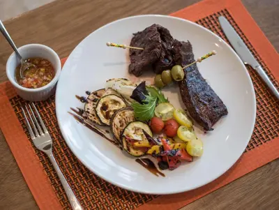 a plate of food with meat and vegetables on a table at Hampton By Hilton Santo Domingo Airport in Boca Chica