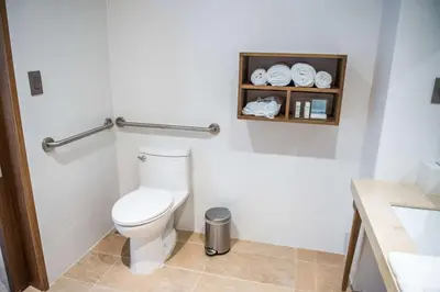 a bathroom with a toilet and a shelf with towels at Hampton By Hilton Santo Domingo Airport in Boca Chica