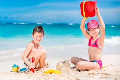 a boy and a girl playing in the sand on the beach at Majestic Elegance Punta Cana - All Inclusive in Punta Cana