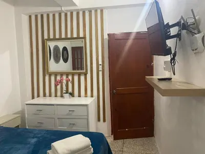 a bathroom with a bed and a sink and a television at Apartamentos Magallanes Romana in La Romana