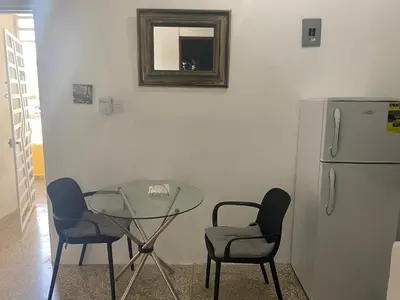 a glass table and two chairs and a refrigerator at Apartamentos Magallanes Romana in La Romana