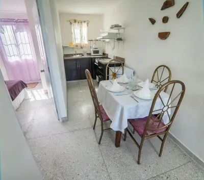 a dining room table with a white table cloth and chairs at Apartamentos Magallanes Romana in La Romana
