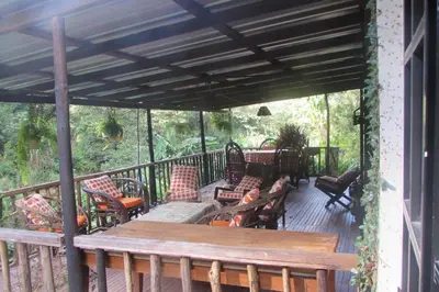a porch with a wooden table and chairs on it at Arroyo Frío River Lodge in Arroyo Frío