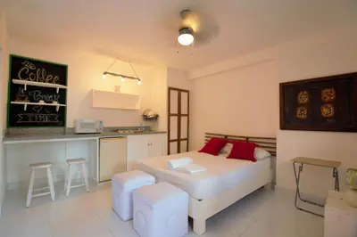 a living room with a bed and a kitchen at La Puerta Roja Guest House in Santo Domingo