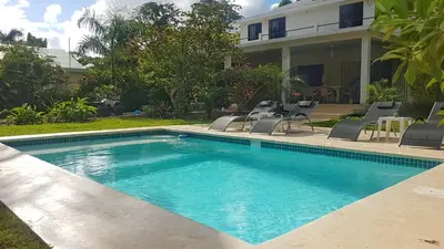 a swimming pool with chairs and a house at La Belle Créole in Las Galeras