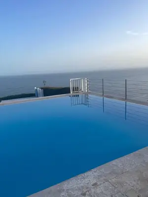 a swimming pool with the ocean in the background at Spectacular Ocean View Top Floor 1-Bedroom Condo, Vista Mare, Samana DR in Santa Bárbara de Samaná