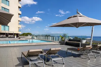 a group of chairs and an umbrella next to a pool at Crowne Plaza Santo Domingo by IHG in Santo Domingo