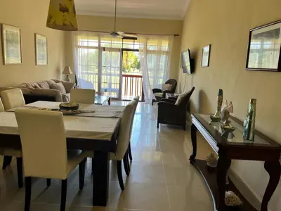 a dining room and living room with a table and chairs at Residencial Green Paradise at Metro Country Club Juan Dolio - 2 Bedroom with Balcony in Juan Dolio