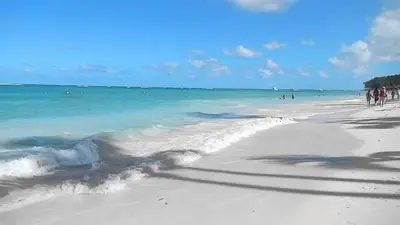 a beach with people in the ocean and the water at Caribbean Treasure in Punta Cana