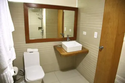 a bathroom with a toilet and a sink and a mirror at Aparta Hotel Plaza del Sol in Santo Domingo