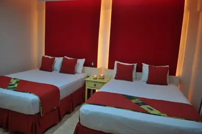 two beds in a hotel room with red walls at Hotel & Casino Flamboyan in Punta Cana