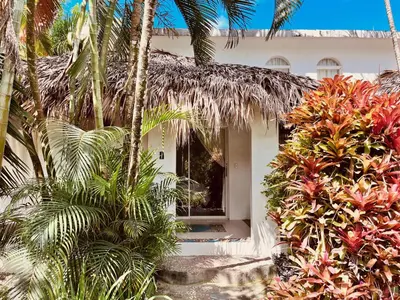 a white house with palm trees in front of it at Hotel La Tortuga in Las Terrenas