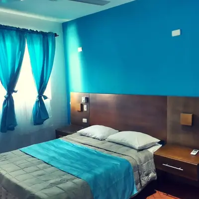 a bedroom with a bed with a blue wall at Figaro Hotel Samana in Santa Bárbara de Samaná