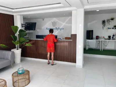 a woman in a red dress standing at a counter at Hotel Neptuno Refugio in Boca Chica