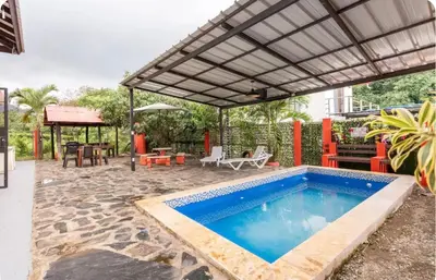 a swimming pool with a pergola next to a house at Cabaña Don Tobo Jarabacoa RD in Jarabacoa