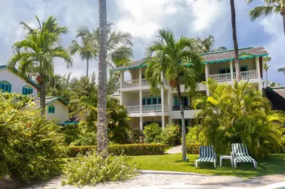 a large white building with palm trees in front of it at Hotel Playa Colibri in Las Terrenas