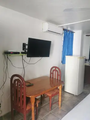 a wooden table with two chairs and a television on a wall at Perla de Sosua in Sosúa
