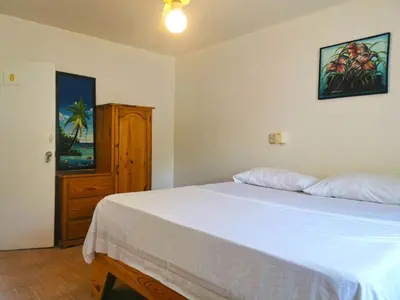a bedroom with a white bed and a wooden cabinet at Perla de Sosua in Sosúa