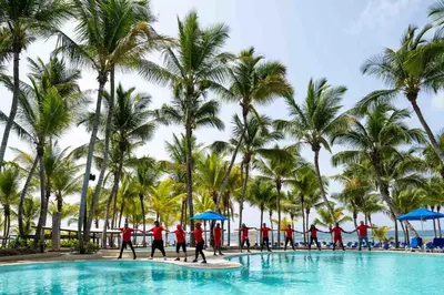 a group of people walking around a pool at a resort at Coral Costa Caribe Beach Resort - All Inclusive in Juan Dolio