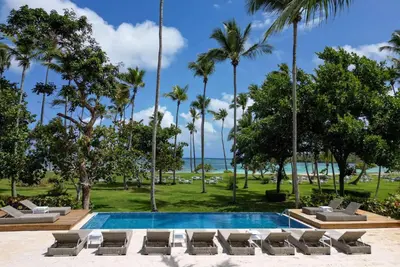 a resort pool with lounge chairs and palm trees at Wyndham Alltra Samana All Inclusive Resort in Las Galeras
