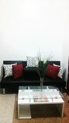 a living room with a black couch and a table at Apartamento Frente Al Mar in San Felipe de Puerto Plata