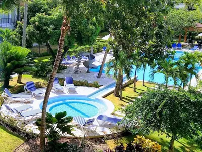 an outdoor swimming pool with chairs and a resort at Comfortable Apartment in Caribbean Paradise in Sosúa