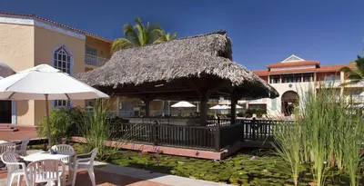 a restaurant with a straw umbrella and tables and chairs at VH - Gran Ventana Beach Resort in San Felipe de Puerto Plata