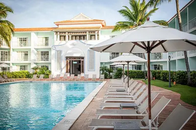 a pool with chairs and umbrellas in front of a building at VH - Gran Ventana Beach Resort in San Felipe de Puerto Plata