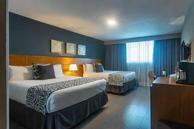 a hotel room with two beds and a television at Hotel Aladino in Santo Domingo