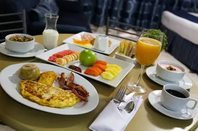 a table with plates of breakfast food and a glass of orange juice at Hotel Aladino in Santo Domingo