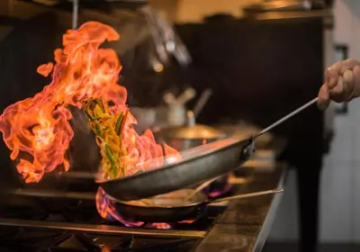 a person cooking food in a pan on a stove at Natura Cabana Boutique Hotel & SPA by Mint in Cabarete