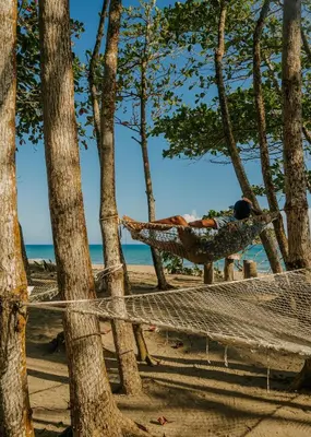 a man laying in a hammock on the beach at Natura Cabana Boutique Hotel & SPA by Mint in Cabarete