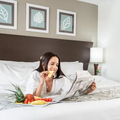 a woman laying on a bed reading a newspaper at Hodelpa Centro Plaza in Santiago de los Caballeros