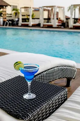 a drink on a table next to a swimming pool at Hodelpa Gran Almirante in Santiago de los Caballeros