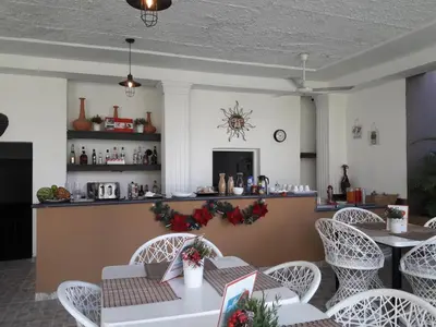 a restaurant with white tables and chairs and a counter at Hotel Marimba Punta Cana in Punta Cana