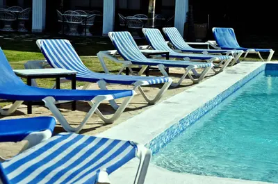 a row of lawn chairs next to a swimming pool at Hotel Marimba Punta Cana in Punta Cana