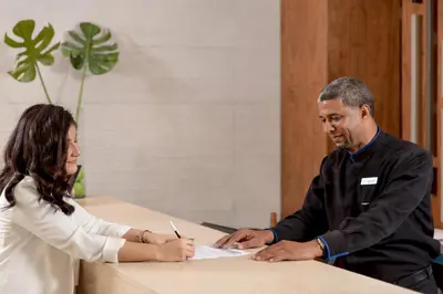 a man and a woman sitting at a desk signing at Hodelpa Caribe Colonial in Santo Domingo