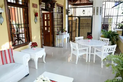 a living room with white tables and white chairs at Hostal Bella Epoca in Santo Domingo