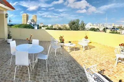 a patio with white chairs and tables and a yellow wall at Hostal Bella Epoca in Santo Domingo