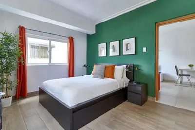 a bedroom with a bed and a green wall at Central Park Tower in Santo Domingo