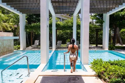 a woman in a bikini walking into a swimming pool at Vista Sol Punta Cana Beach Resort & Spa - All Inclusive in Punta Cana