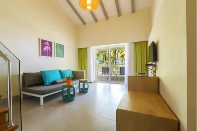 a living room with a couch and a tv at Vista Sol Punta Cana Beach Resort & Spa - All Inclusive in Punta Cana