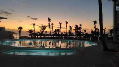 a pool with palm trees and a sunset in the background at 1 Sol Dominicus Solo Adultos Habitación con Entrada Independiente y Baño Privado in Bayahibe